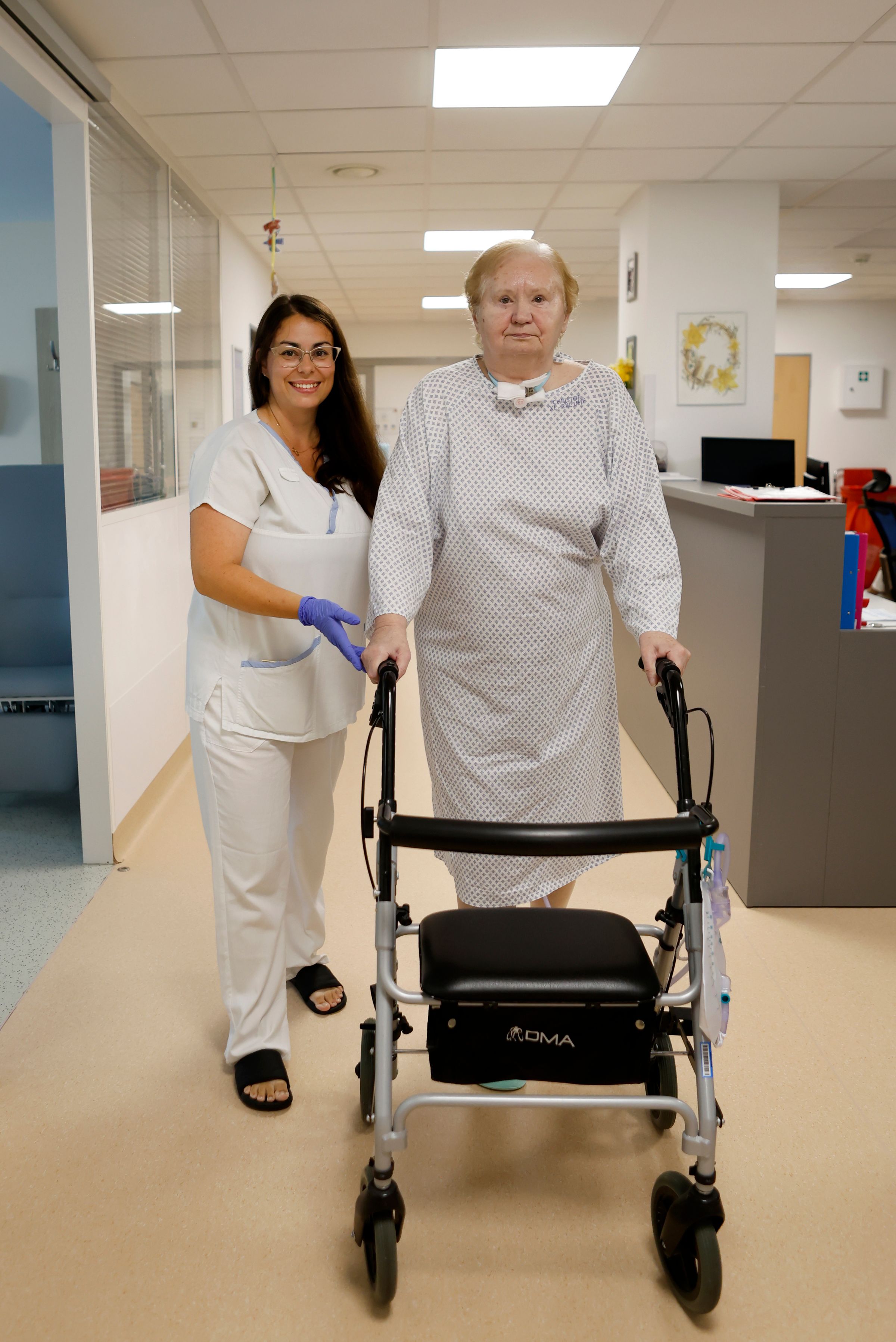 Pracovnice pomáhá muži při chůzi s chodítkem