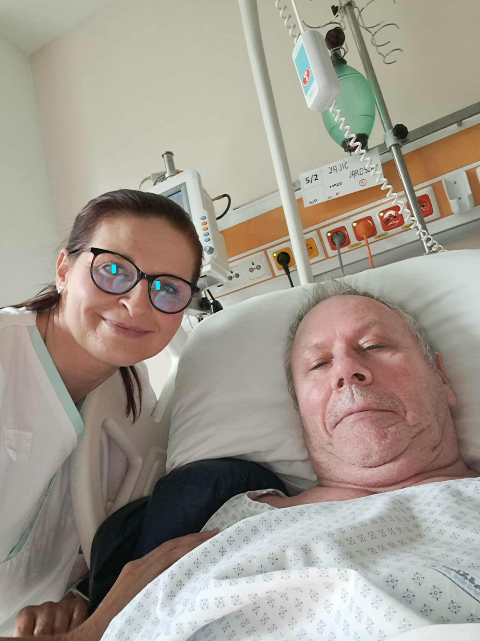 Žena s brýlemi vedle pacienta na lůžku