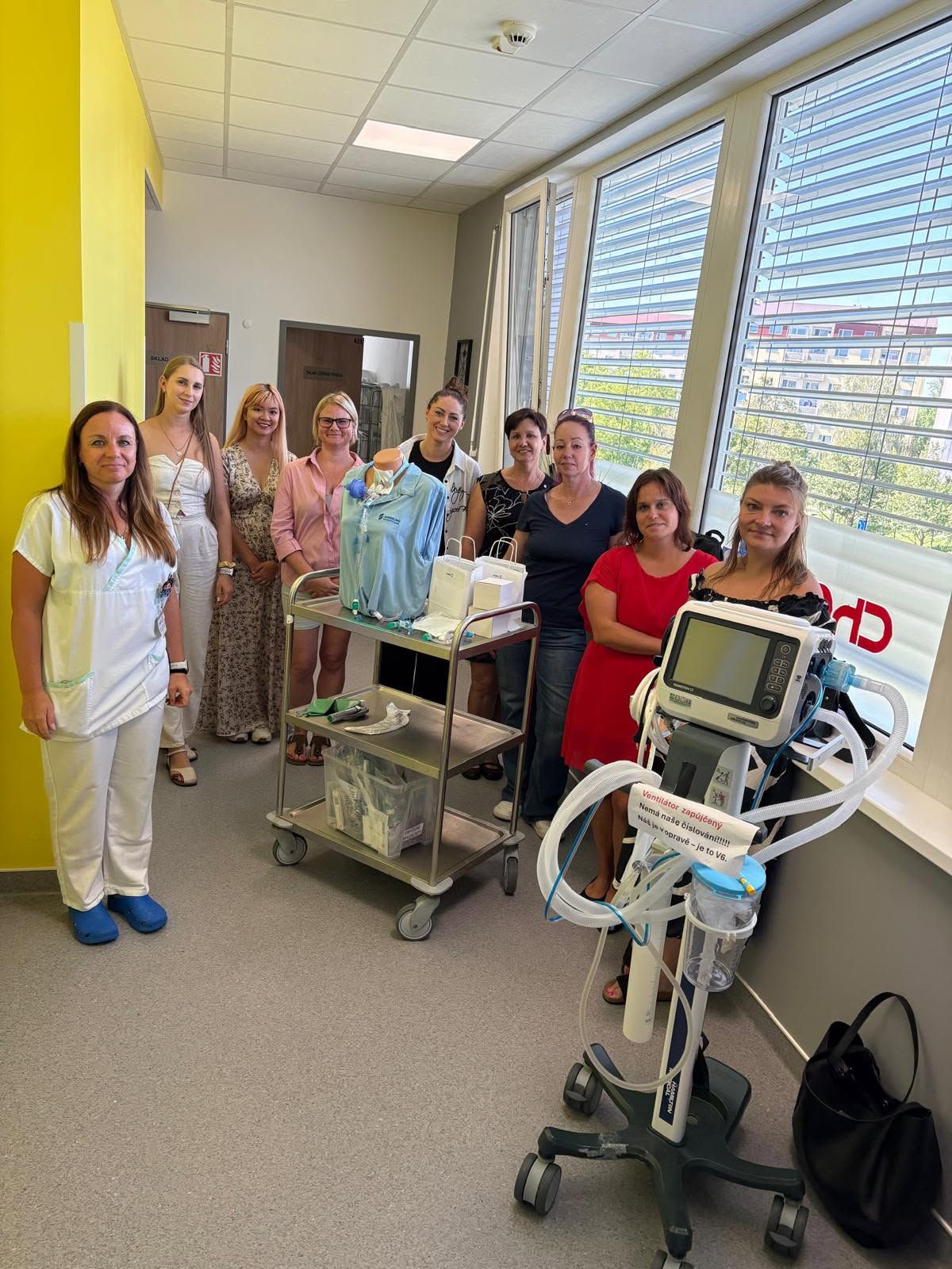 Skupina žen na oddělení vedle nemocničního lůžka a zdravotnických přístrojů.