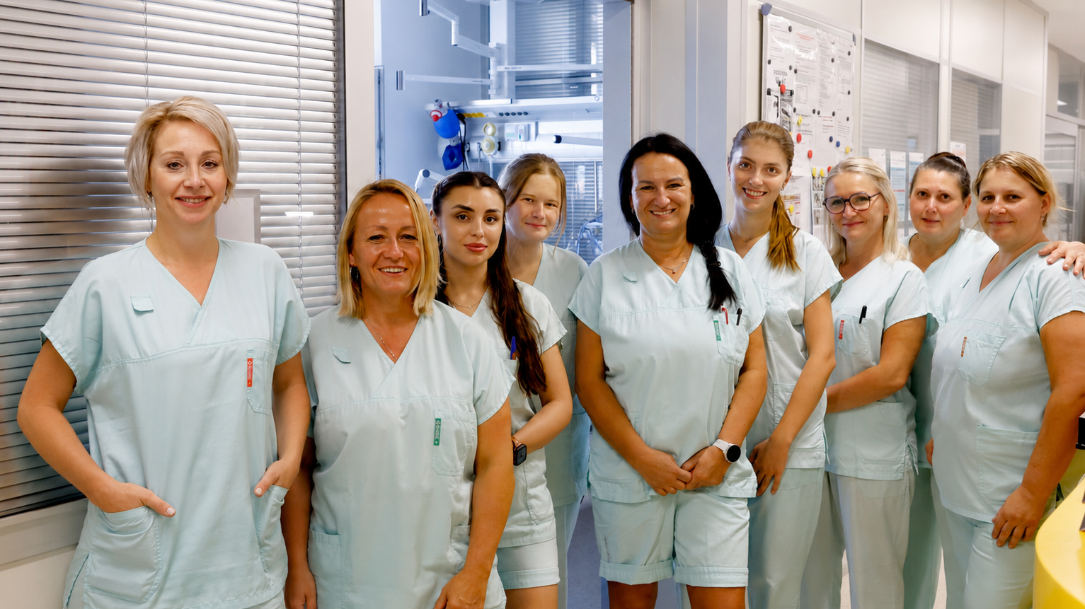 Skupina zdravotnic při společném fotografování na chodbě pracoviště.