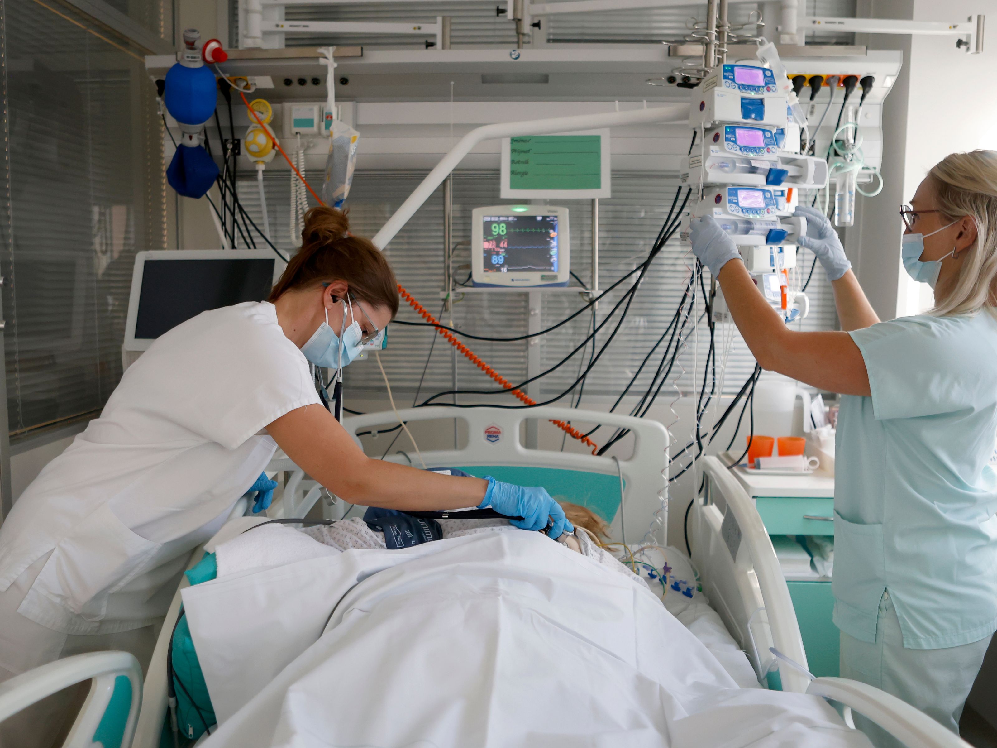 Dvě zdravotnice pečují o pacienta na nemocničním lůžku.