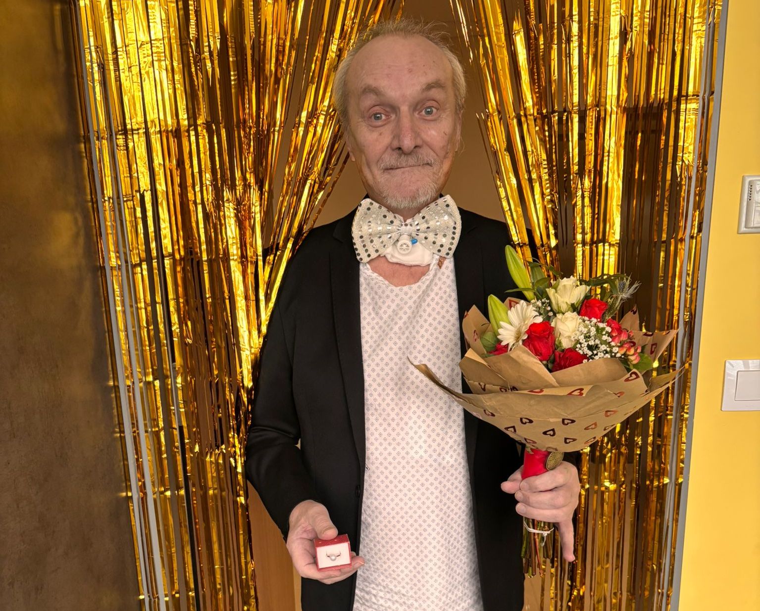 Václav s kyticí před zlatým závěsem.